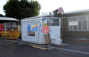 External view during works, sowing scaffolding and skip, with contractors working on the roof.