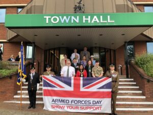 Unit and Council members stand on the steps of the Town Hall with Armed Forces Day flag.