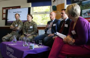 The panel are sitting around a low table facing the audience, whilst one employer is speaking in to a microphone to answer a panel question.