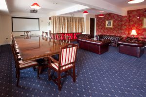 A room with a table and chairs and some sofa seats.