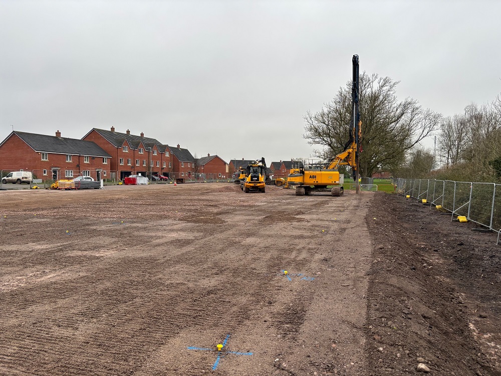 Building site, mostly mud, with diggers working on site.