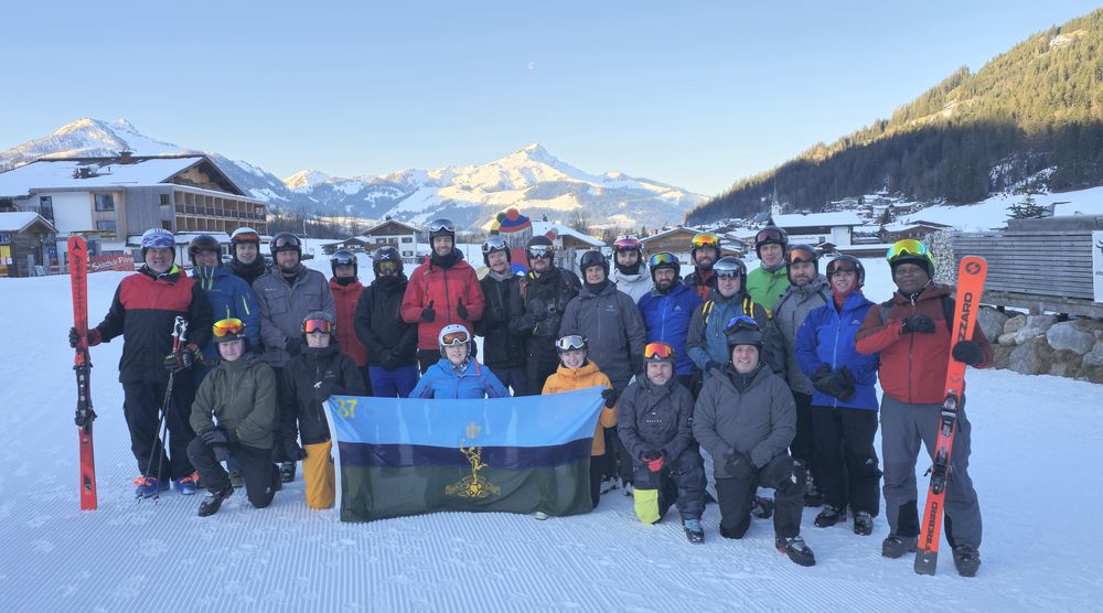 Group photograph of all attendees on the snowy slope with snowy mountains in the background.